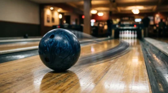 Boule de bowling en pleine trajectoire courbe sur piste avec effet de rotation visible