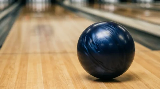 Boule de bowling en pleine rotation avec effet hook marqué sur piste huilée