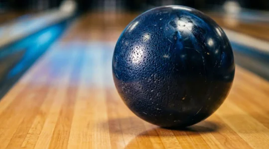 Gros plan d'une boule de bowling en plein mouvement montrant une rotation rapide et dynamique sur la piste