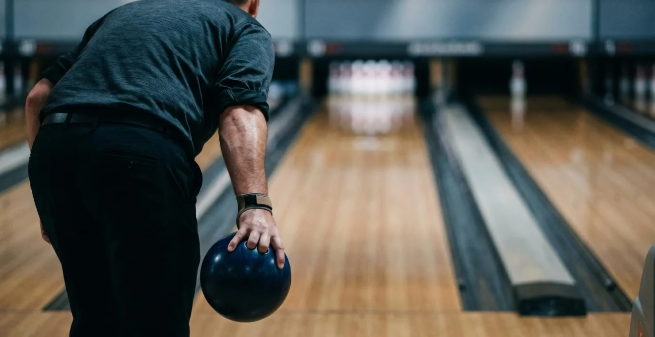 Joueur de bowling en pleine concentration juste avant son lancer décisif sur la piste