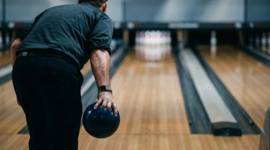 Joueur de bowling en pleine concentration juste avant son lancer décisif sur la piste