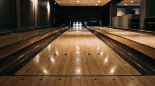 Piste de bowling professionnelle avec zones d'huile visibles, vue en perspective avec éclairage dramatique soulignant les différences de texture entre zones sèches et huilées