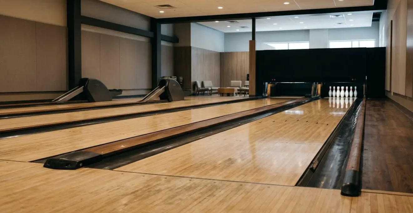 Vue grand angle d'une piste de bowling vide sous un éclairage naturel doux avec espace négatif pour illustrer la structuration d'une séance d'entraînement