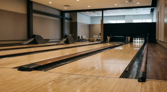Vue grand angle d'une piste de bowling vide sous un éclairage naturel doux avec espace négatif pour illustrer la structuration d'une séance d'entraînement